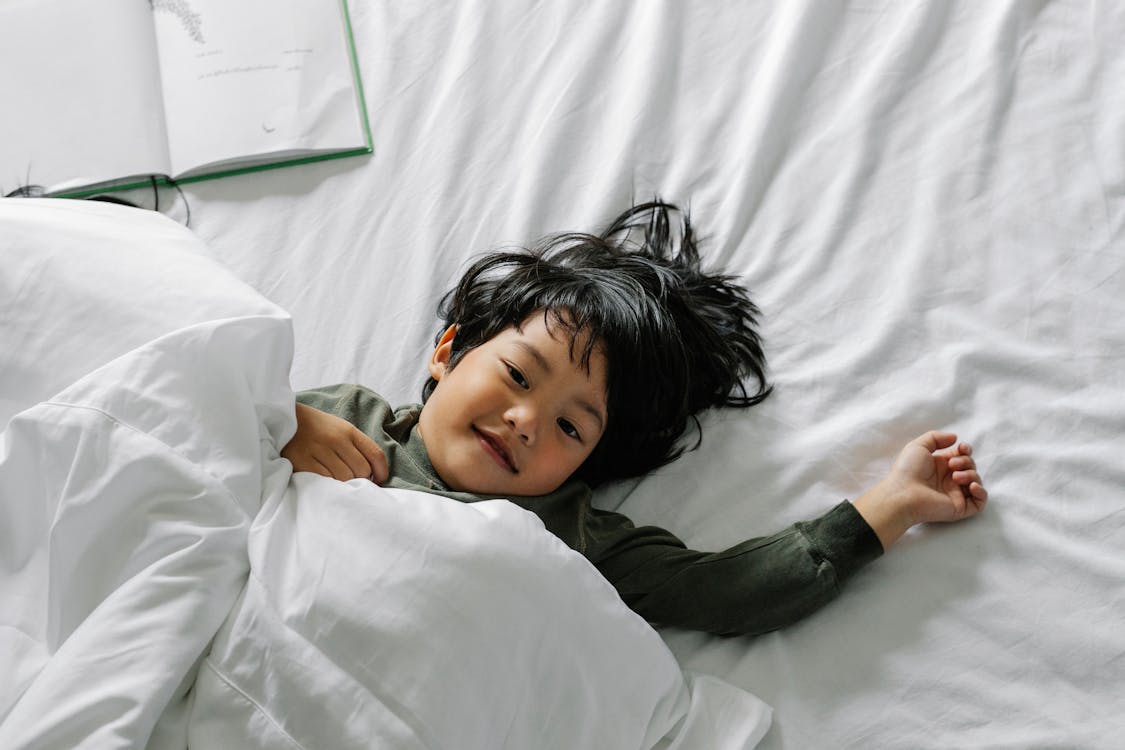 Free Ethnic boy lying in bed after sleep Stock Photo