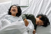 晨光下，两个快乐的孩子一起在舒适的床上欢笑