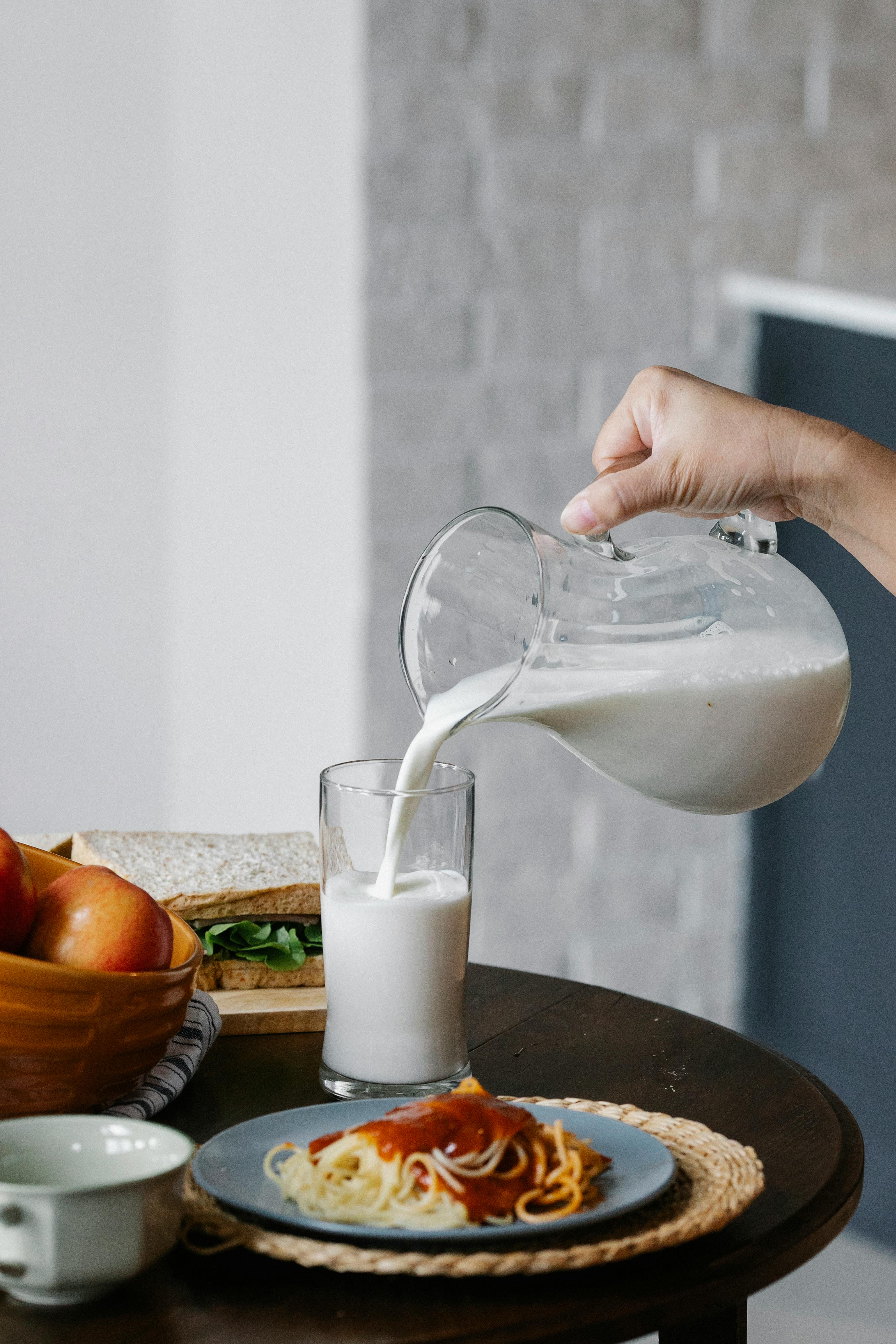 crop person pouring milk in kitchen