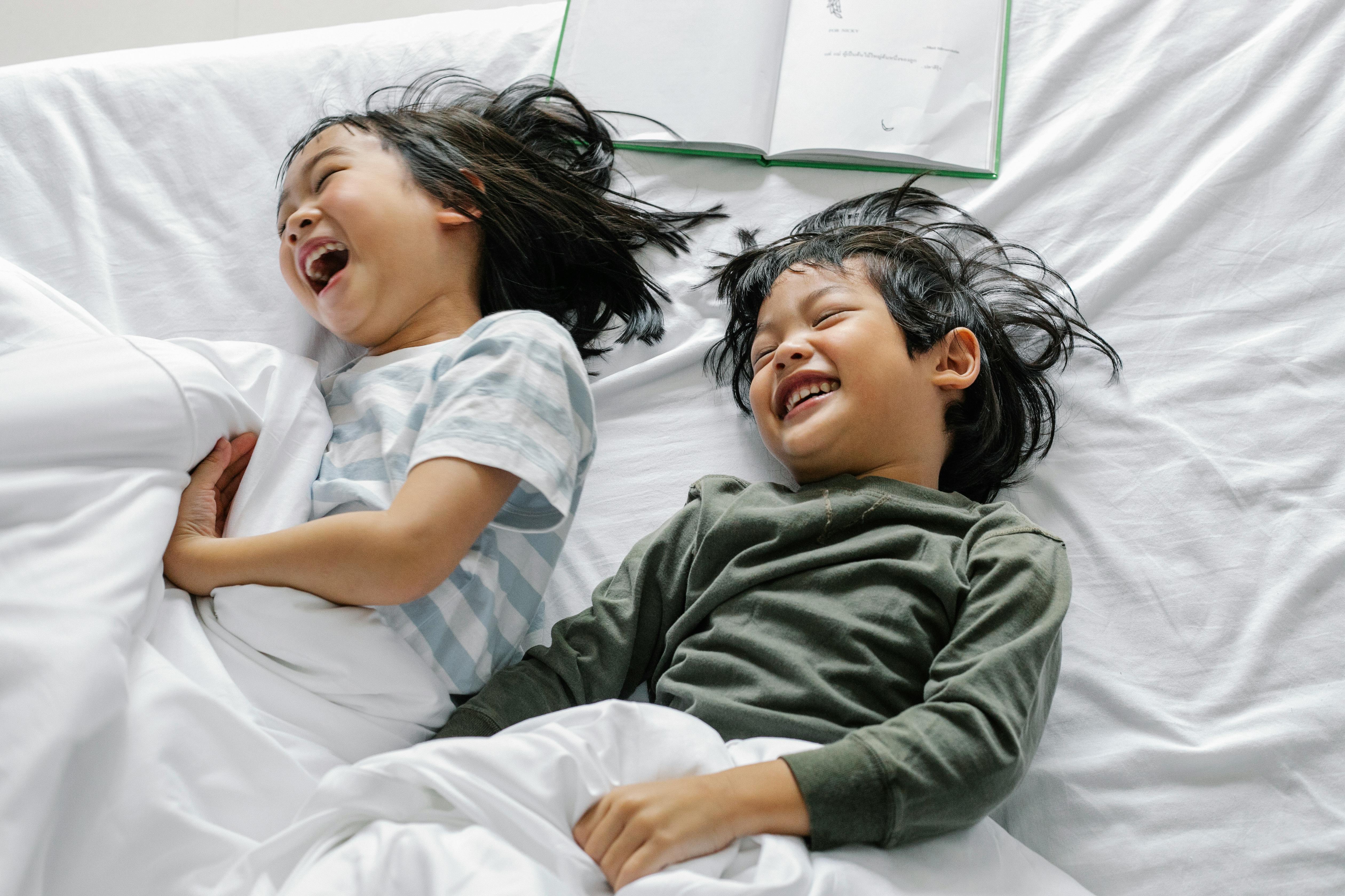 cheerful asian kids having fun in bed