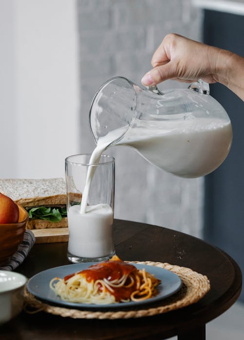 Free Crop person pouring milk in glass Stock Photo