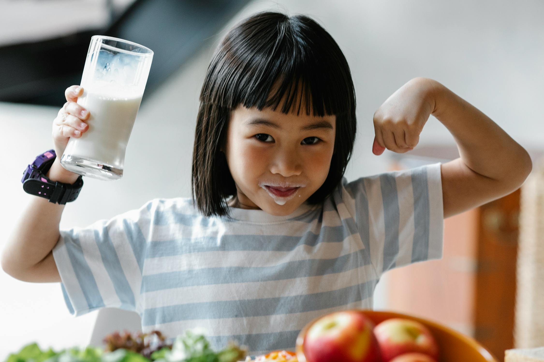 young girl drinking milk and flexing her biceps muscles