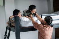 Asian kids on bunk bed near grandmother
