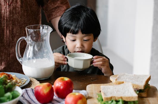 A young boy enjoys a healthy breakfast with milk, apples, and sandwiches, starting his day with nutrition.