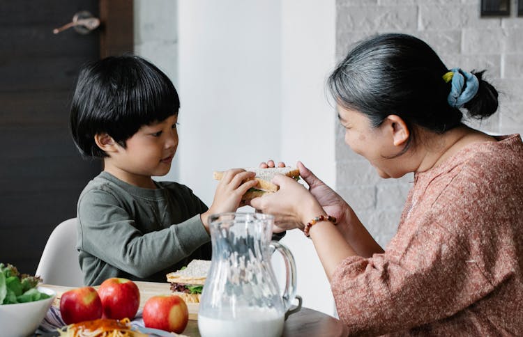 Grandmother Giving Sandwich To Asian Grandson