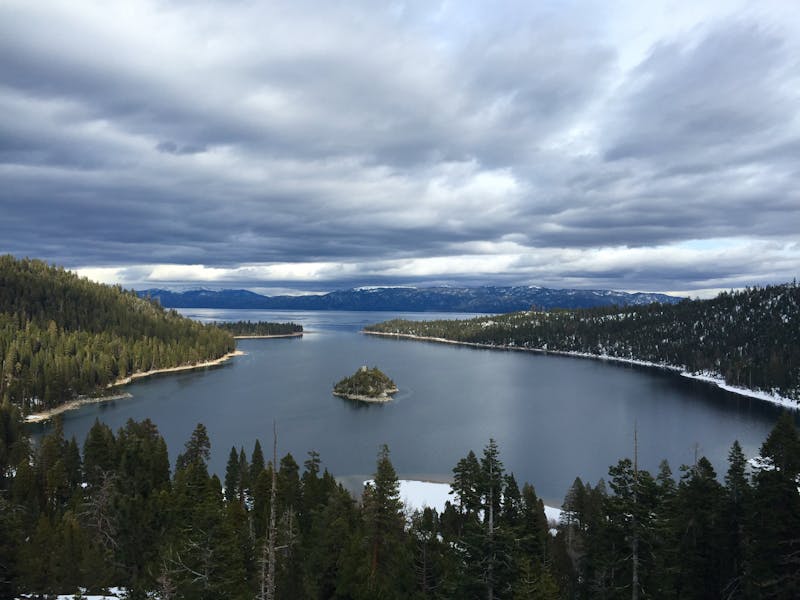 Vue imprenable sur le lac Tahoe avec des forêts de pins et des nuages dramatiques.