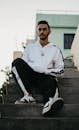 Young Man in Tracksuit Sitting on Steps Outdoors