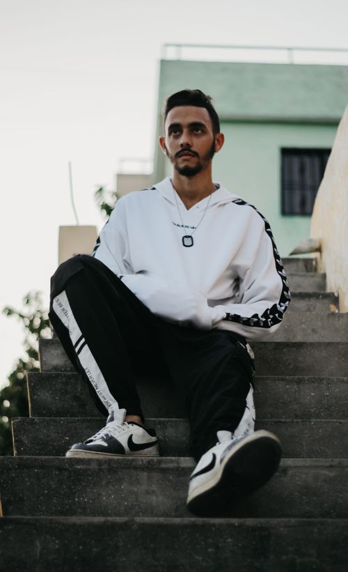 Free A stylish young man wearing streetwear sits on steps outdoors, embodying modern urban fashion. Stock Photo