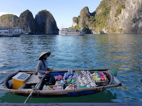在下龙湾令人惊叹的石灰岩风景中，一名小贩在小船上售卖商品