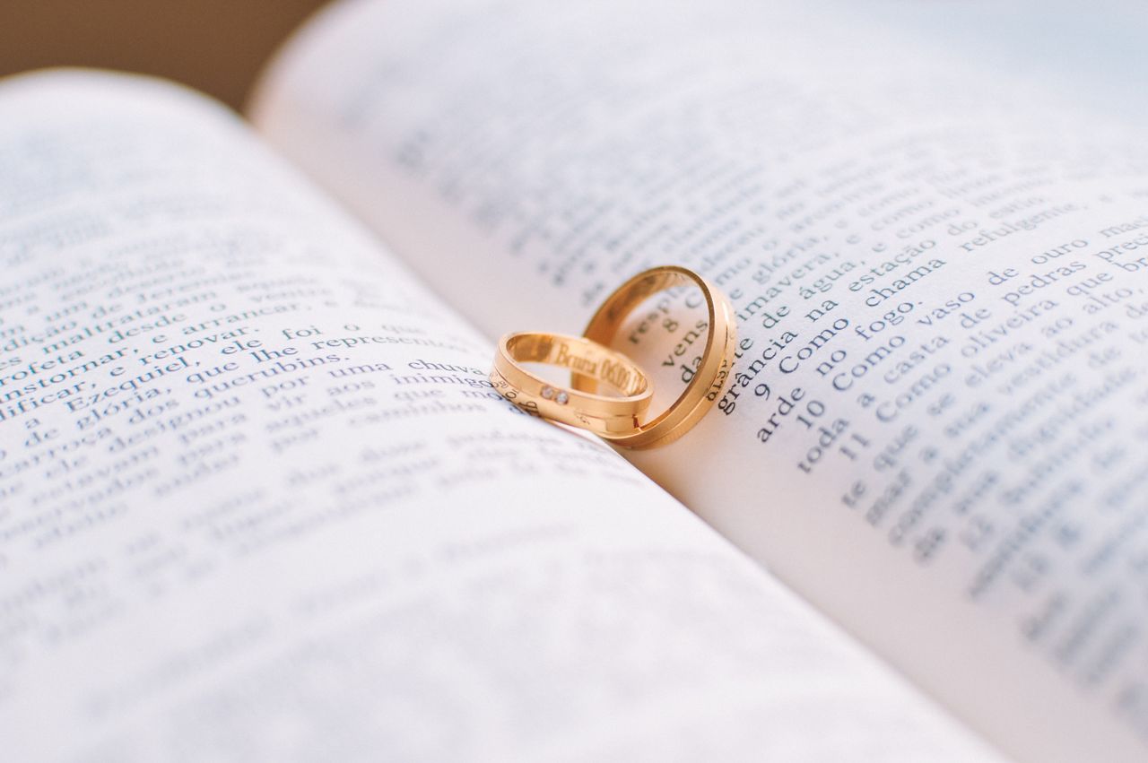 two plain wedding bands resting on a page, illustrating how to choose a wedding band for men