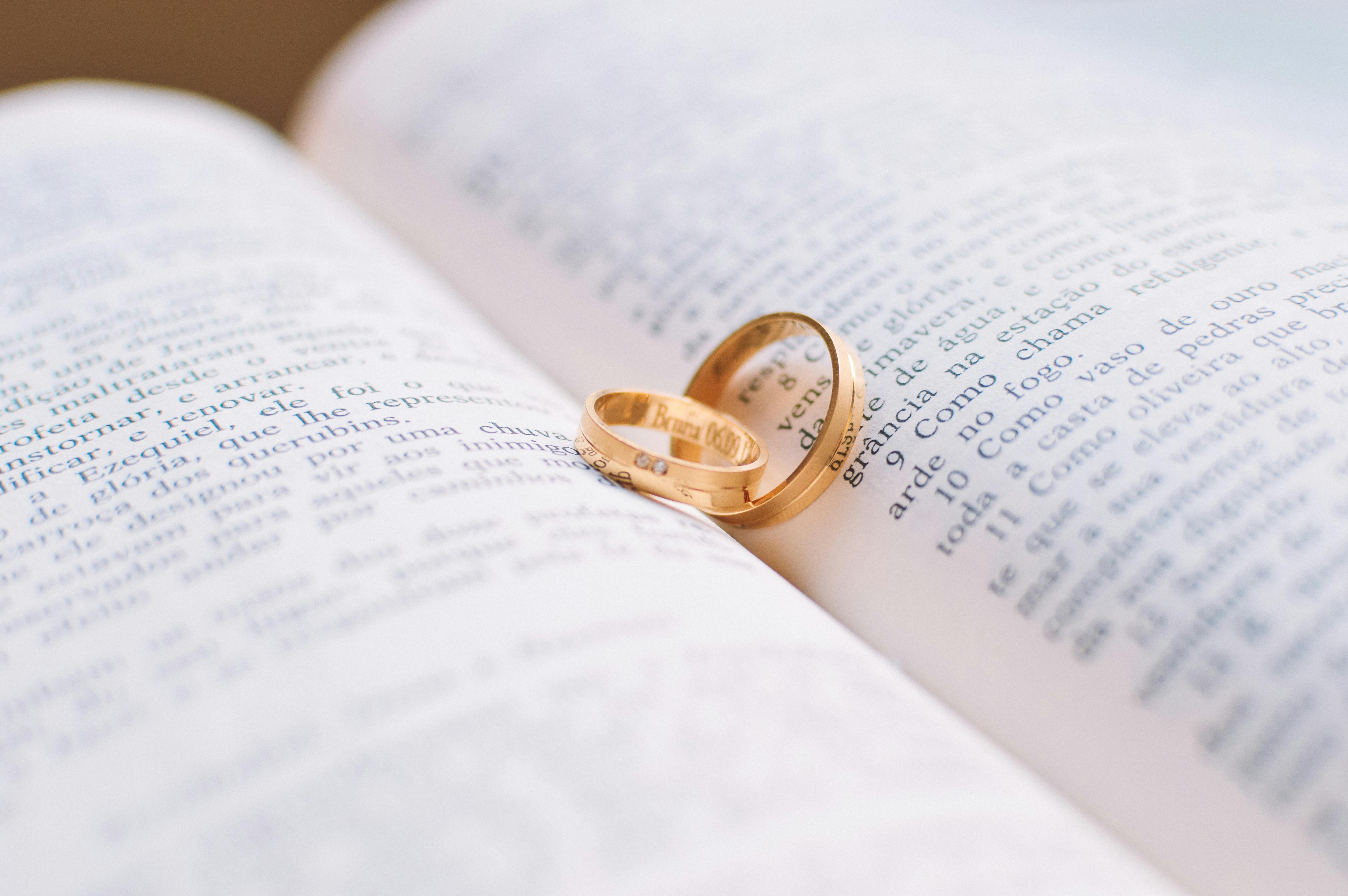 Two Gold-colored Wedding Bands on Book Page \u00b7 Free Stock Photo