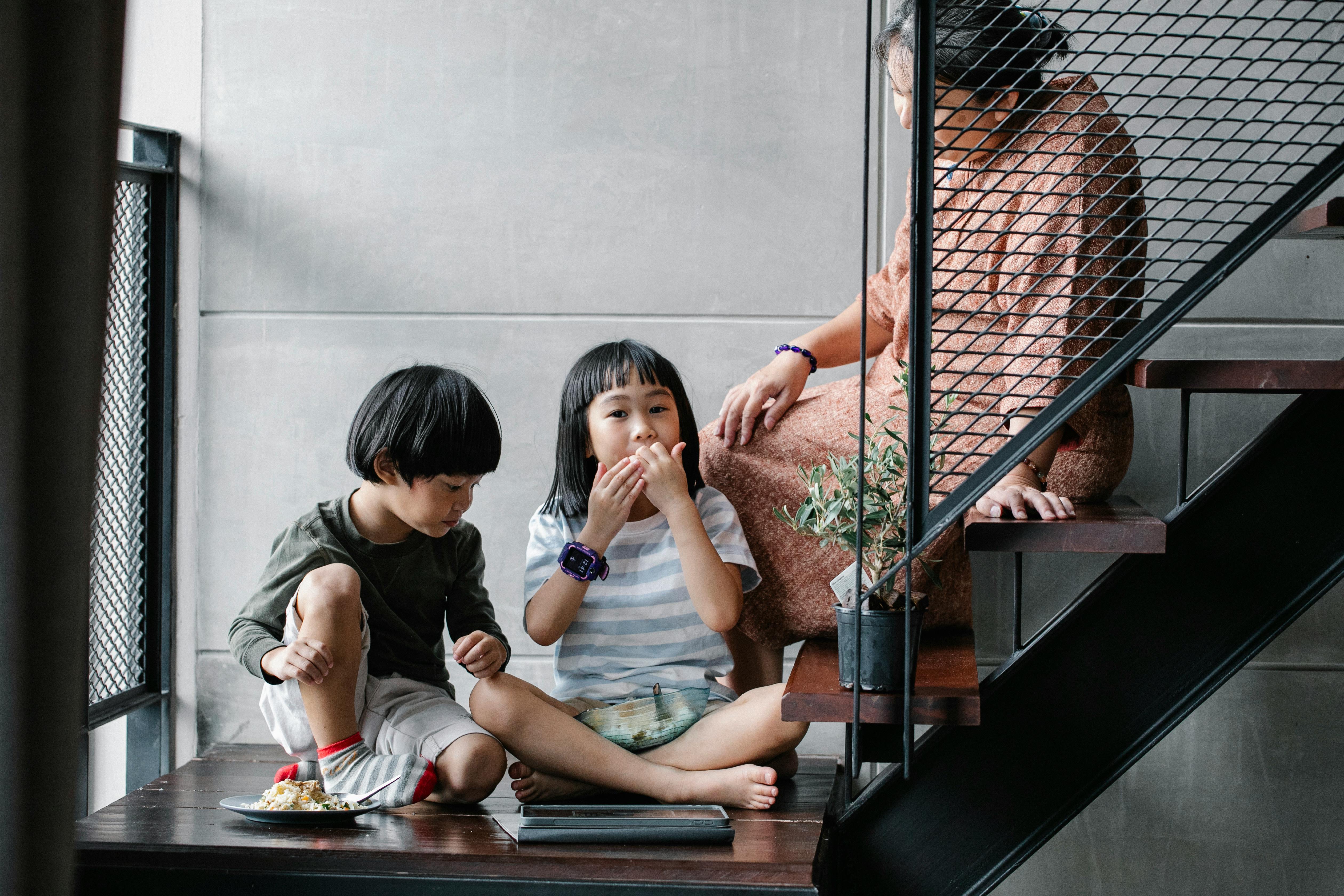 senior ethnic woman with grandchildren relaxing on stairway at home