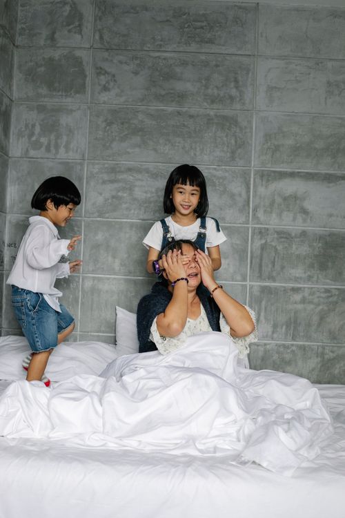 Free Cute active little Asian children playing with happy grandmother sitting on bed in sunny morning Stock Photo