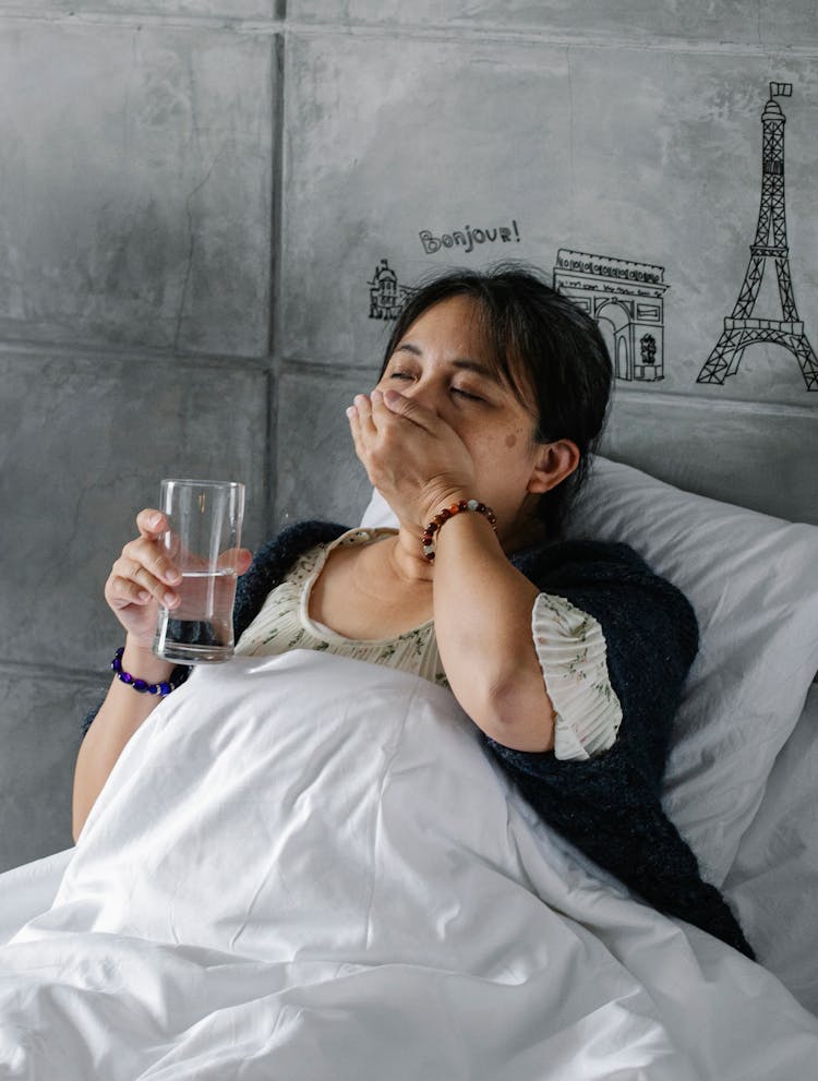 Unhealthy Ethnic Woman Taking Pills While Resting In Bed