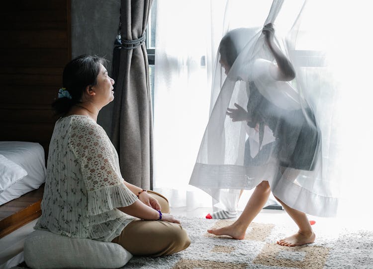 Anonymous Little Girl Having Fun With Asian Grandmother Sitting On Floor In Bedroom