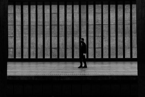 Free A solitary person walking in a grayscale urban train station. Stock Photo