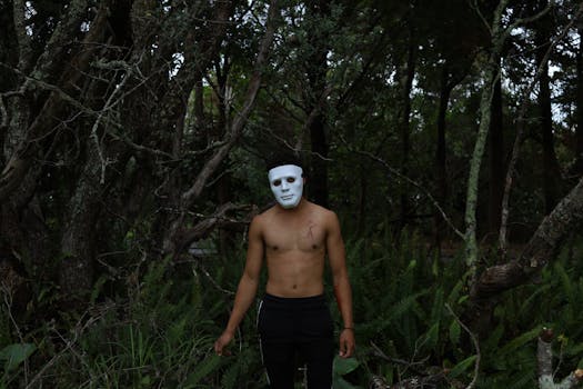 A mysterious figure in a white mask stands in a dark forest. Creepy, intriguing.