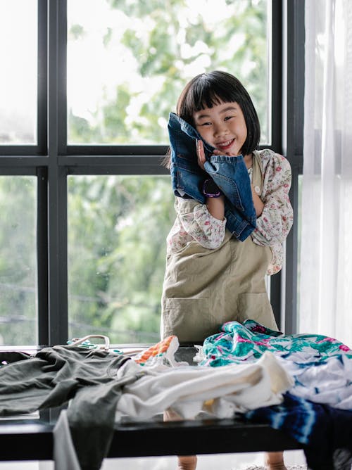 Happy ethnic kid choosing clothes at home