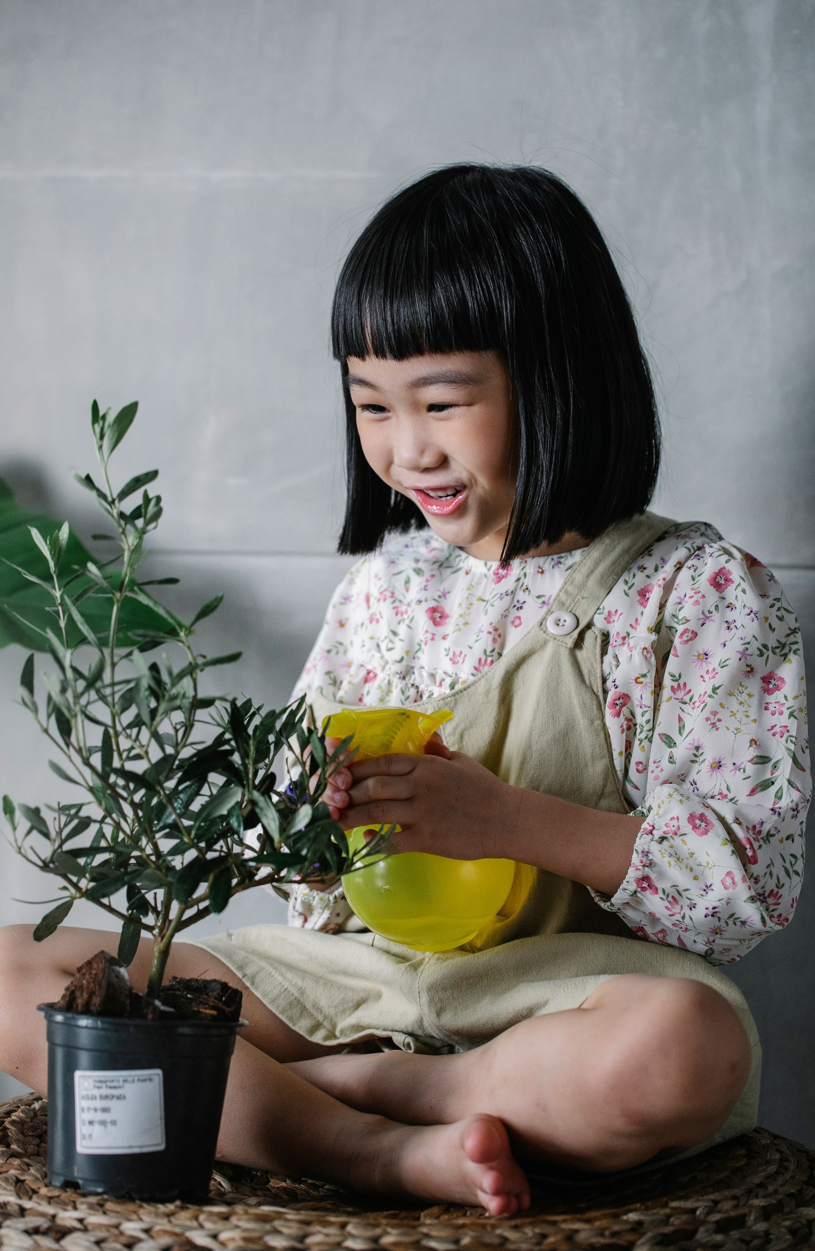 一个快乐的孩子在室内用喷壶照料植物，这带来了欢乐并促进了成长
