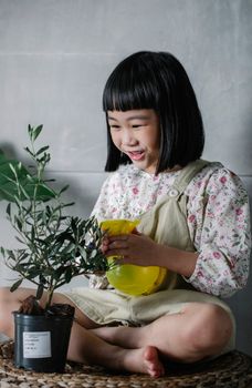 一个快乐的孩子在室内用喷壶照料植物，这带来了欢乐并促进了成长