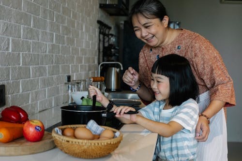 Asian woman with granddaughter preparing food