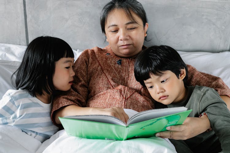 Asian Grandmother Reading Book With Children