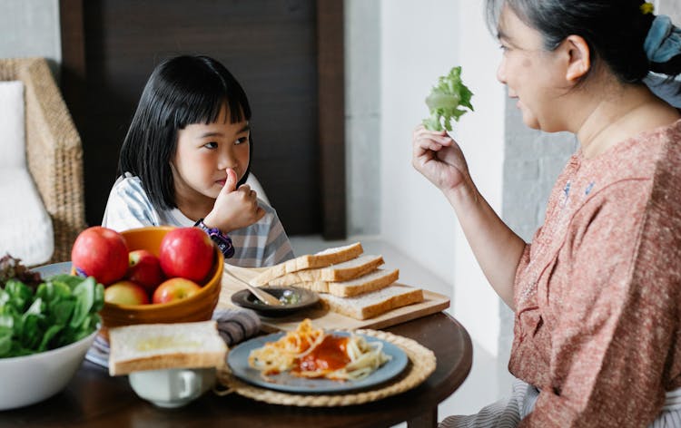 Senior Woman With Granddaughter At Table With Food