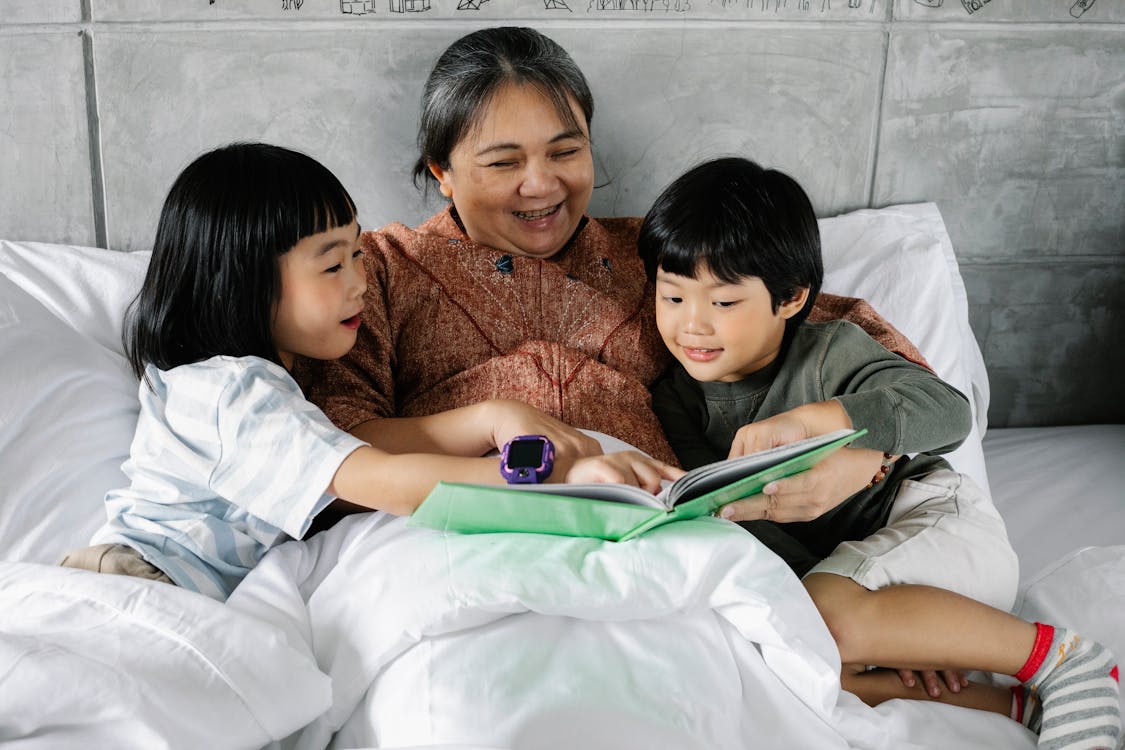 Free Happy ethnic woman and kids reading book together Stock Photo