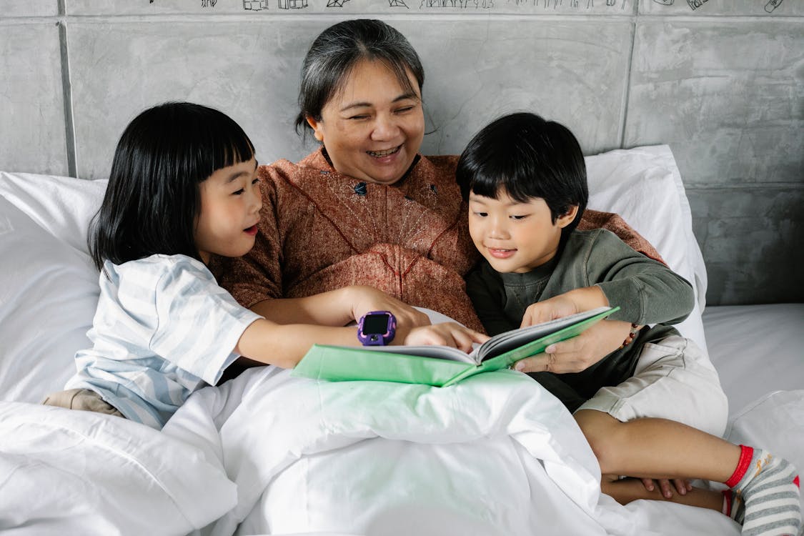 purpose of children's literature Free Happy ethnic woman and kids reading book together Stock Photo