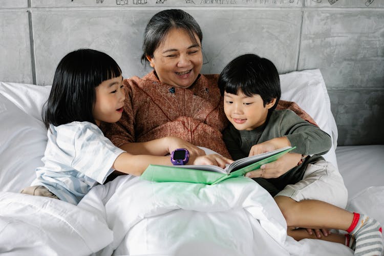 Happy Ethnic Woman And Kids Reading Book Together