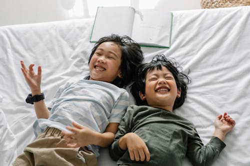 Happy ethnic children lying on bed