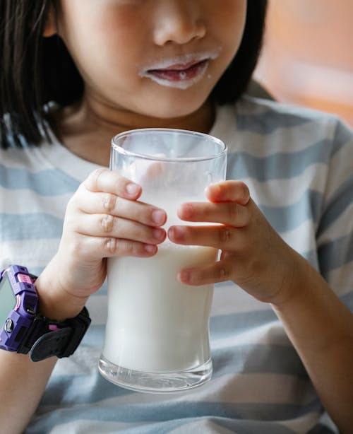 Crop little girl with mouth in milk