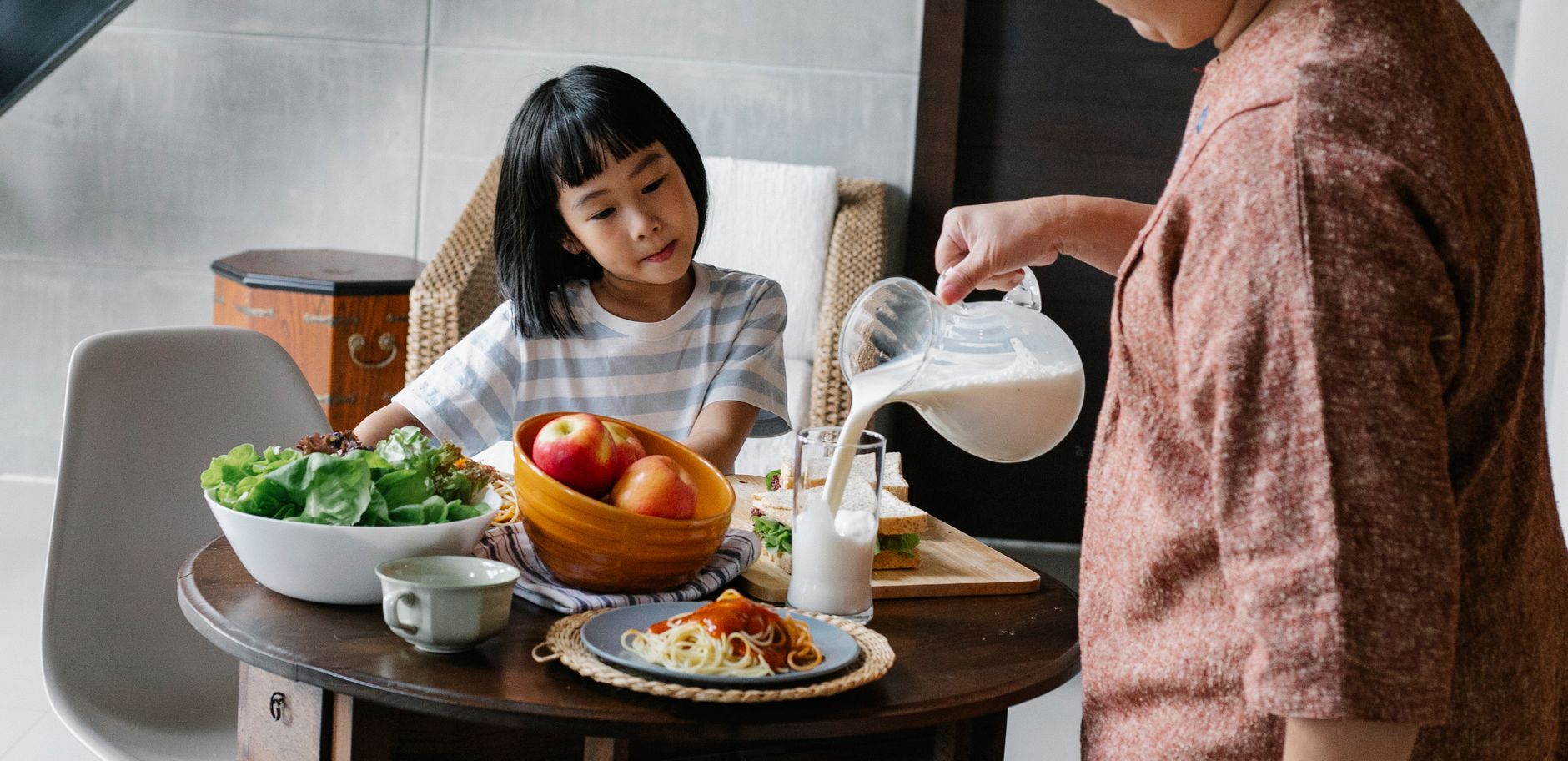 健康飲食與時間管理衝突的實用解法 Crop faceless female standing near table and preparing healthy lunch for cute Asian kid at home