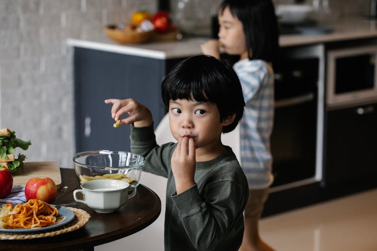 Cute Asian Boy Eating Breakfast At Table