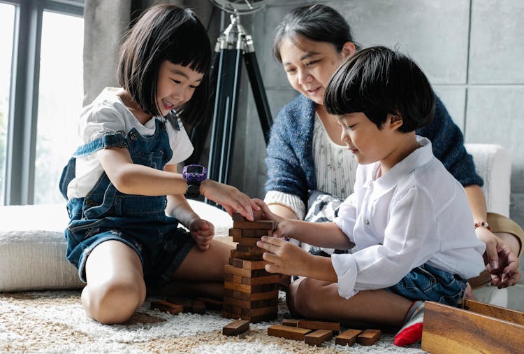 Asian Woman Playing Tower Game With Children