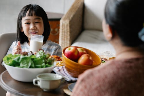 웃 고있는 동안 우유를 마시는 행복 한 아시아 소녀