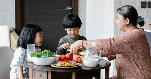 Grandmother having breakfast with Asian children