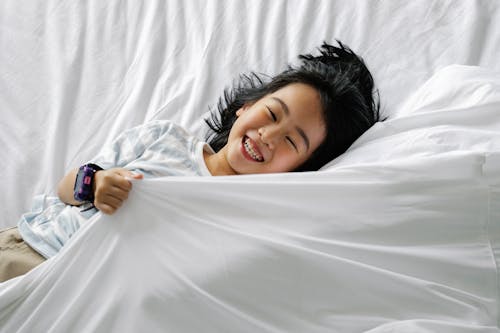 Happy Asian little girl lying on bed