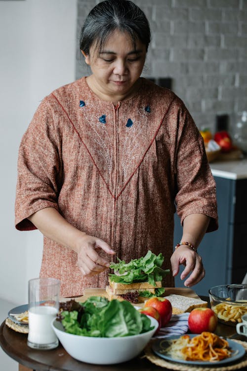 Free Asian senior woman cooking sandwich at home Stock Photo