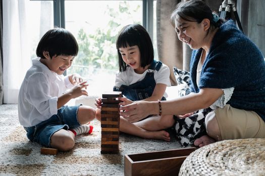 祖母在家盘腿坐在地板上，和孩子们玩塔游戏