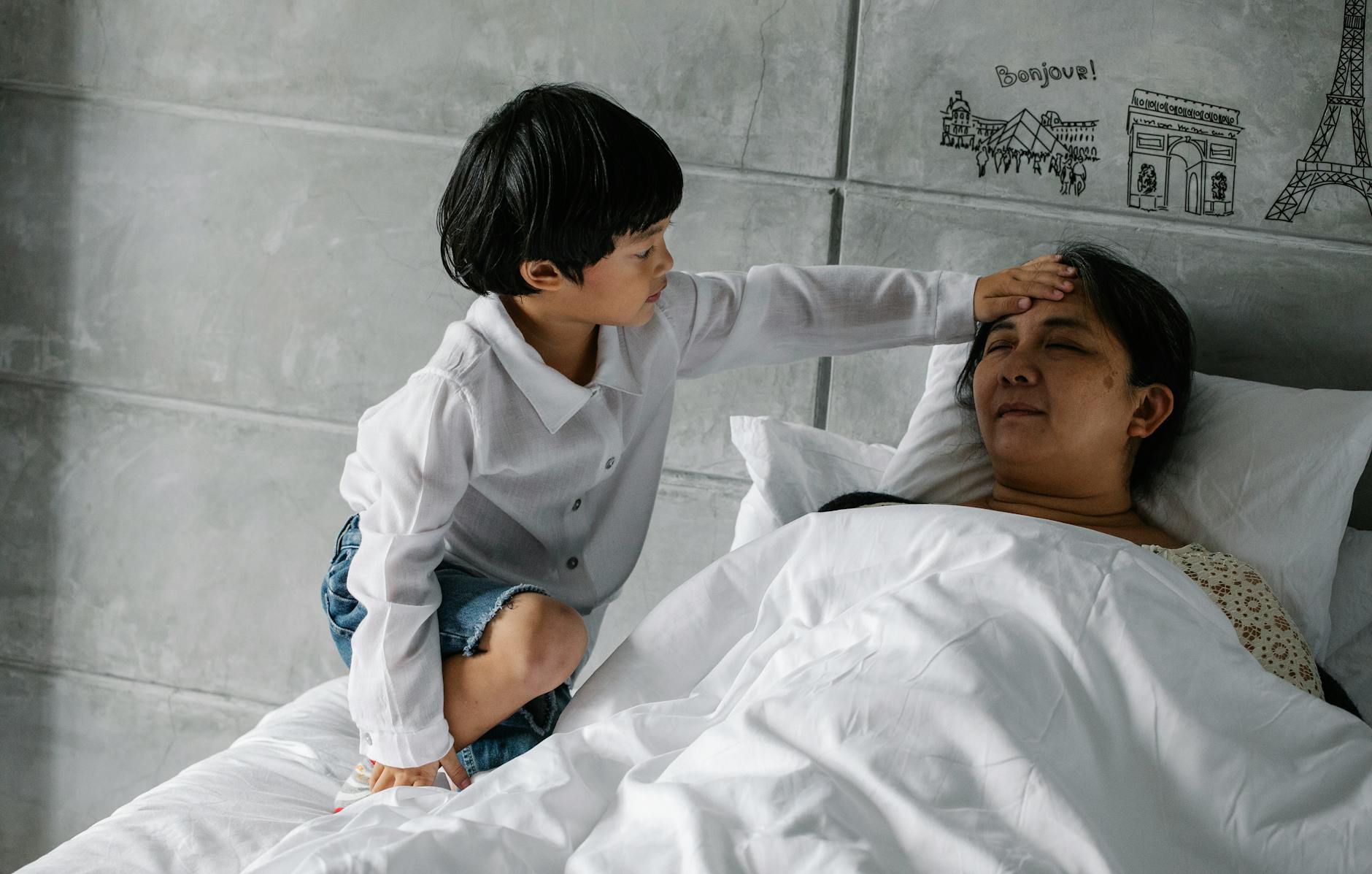 Little Asian boy measuring temperature of sleeping grandmother