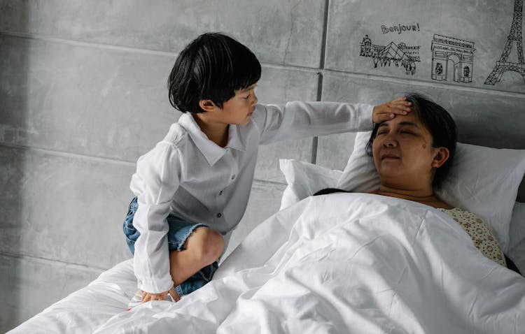 Little Asian Boy Measuring Temperature Of Sleeping Grandmother