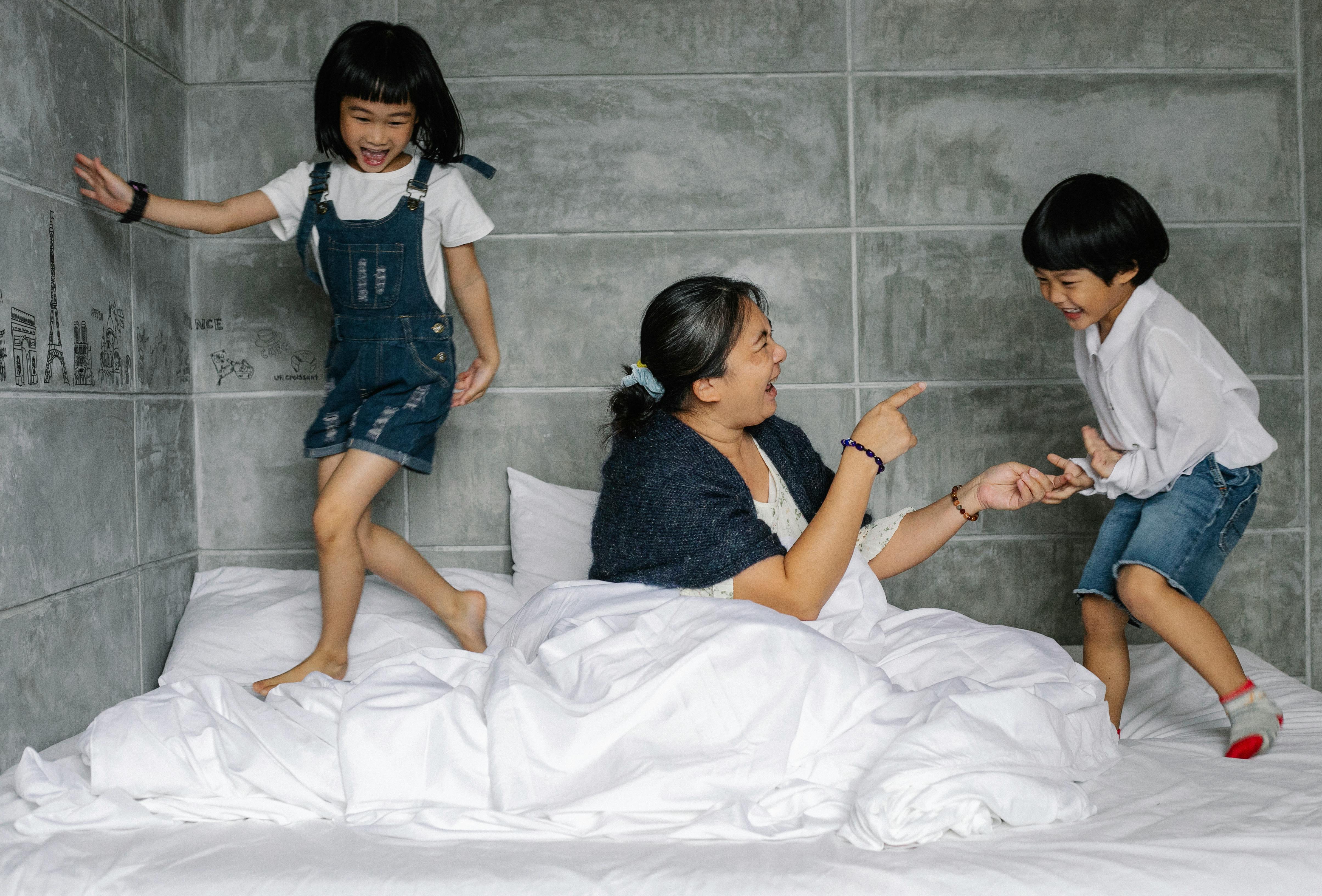 cheerful elderly woman with playful kids on bed