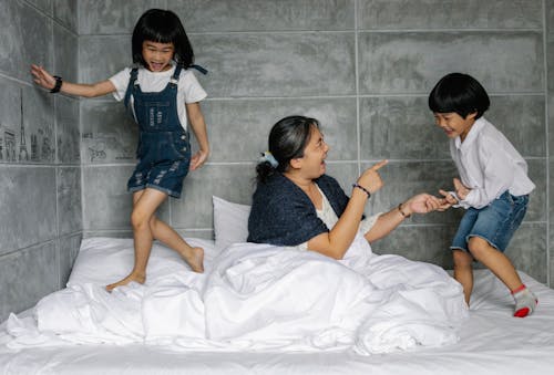 Cheerful elderly woman with playful kids on bed