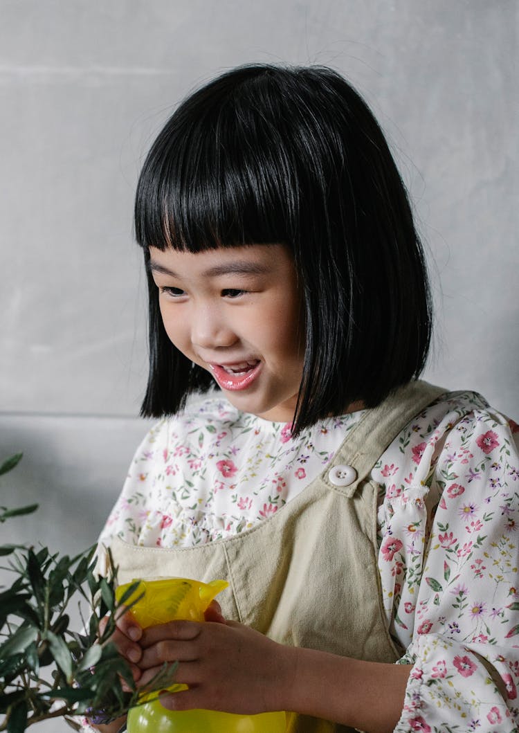 Adorable Little Girl Spraying Green Plant