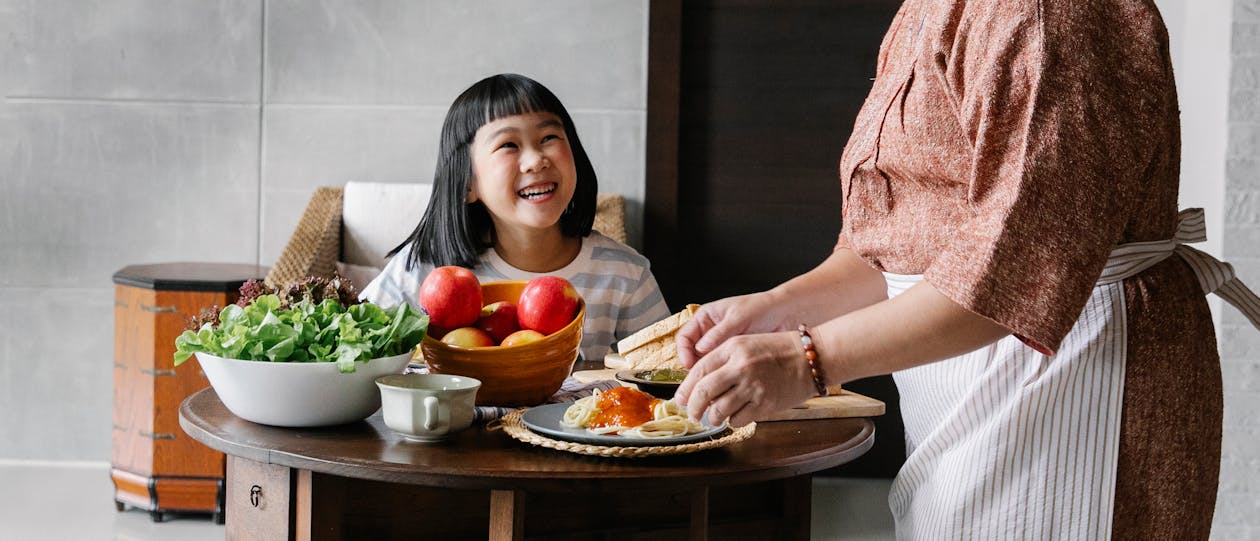 Joyful Asian girl and granny gathering at table for lunch