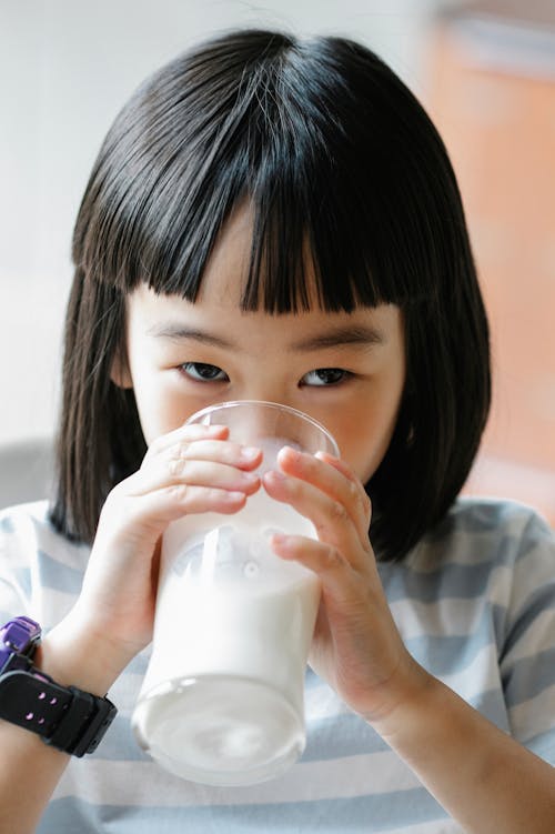 Cute Asian girl drinking milk from glass