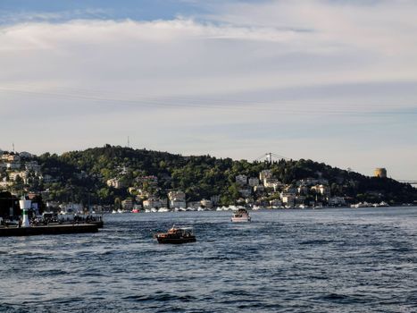 A picturesque view of boats navigating the Bosphorus Strait in Beşiktaş, Istanbul, with a backdrop of lush hills and cityscape.