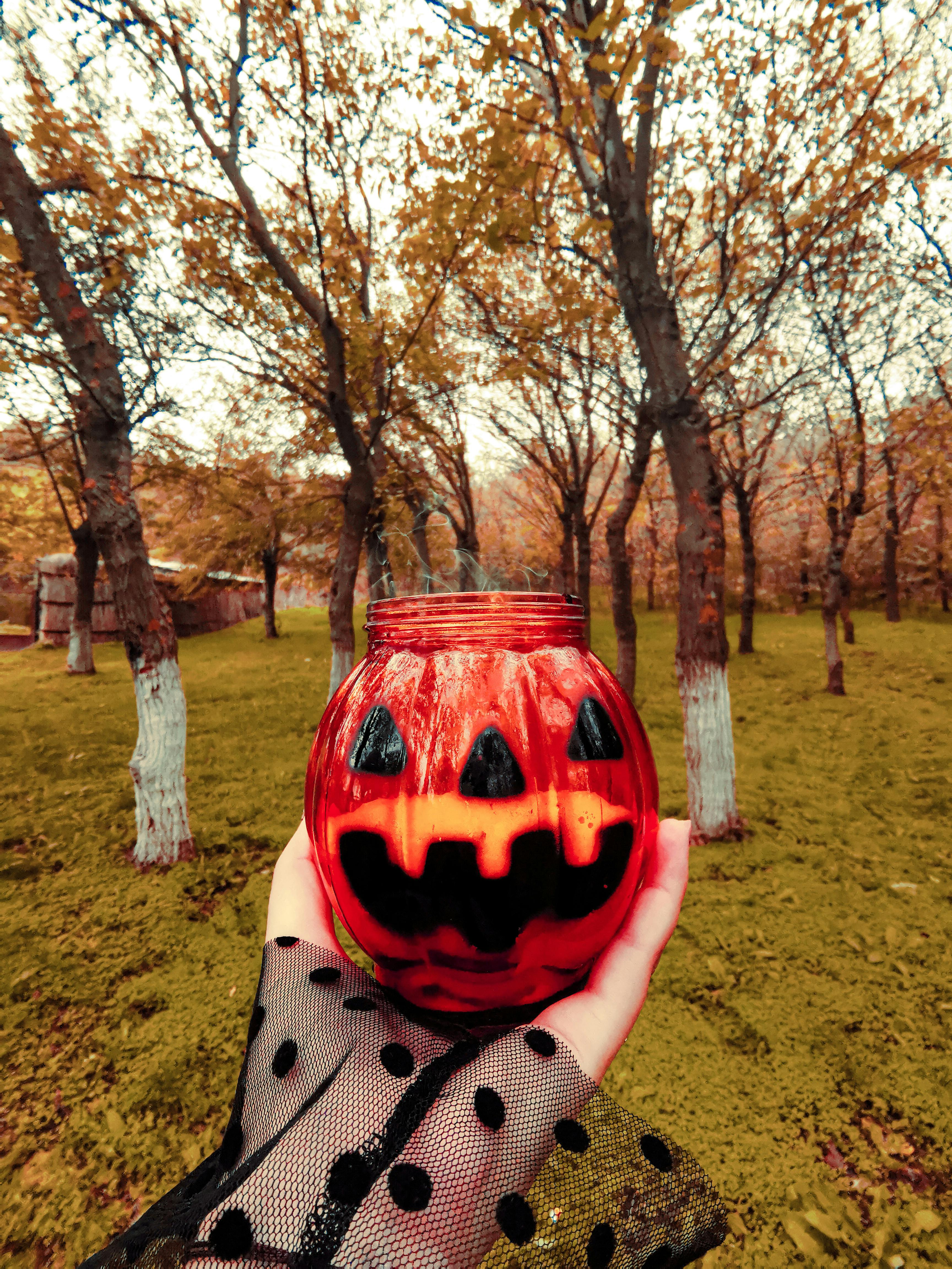 person holding a jack o lantern glass jar