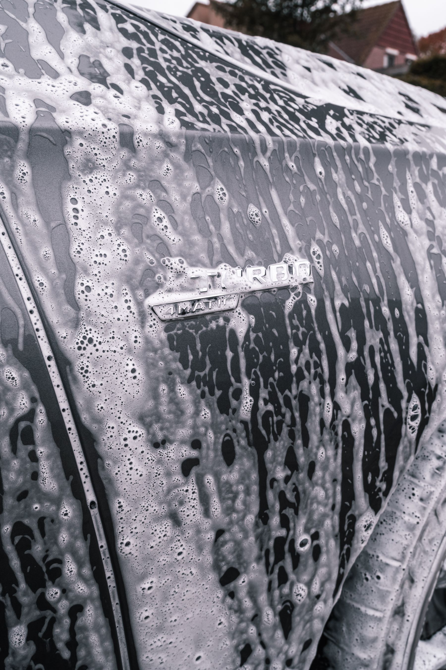 Détail de carrosserie en lavage avec eau et reflets.